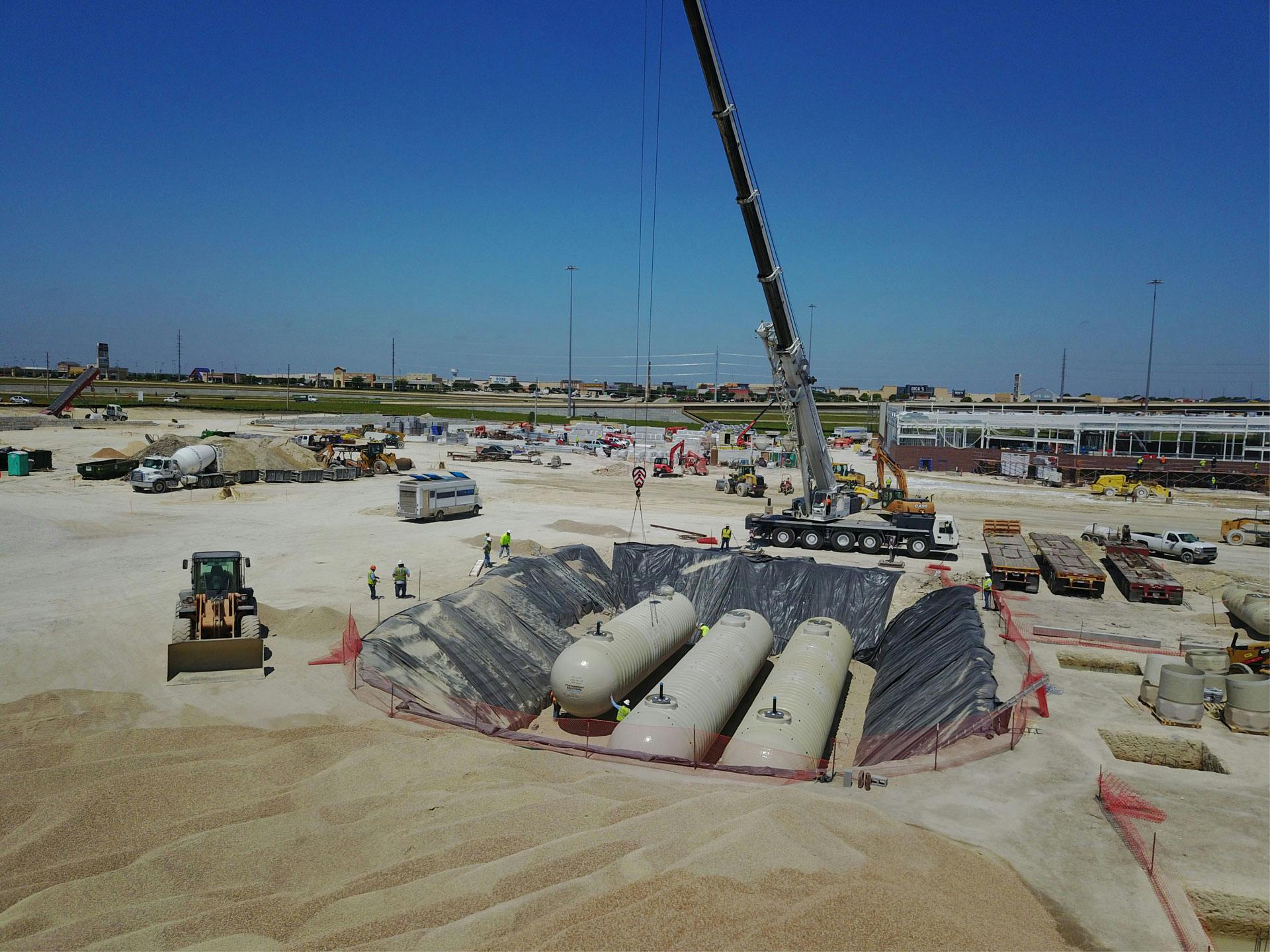 Tanks on job site being lowered into excavated area.