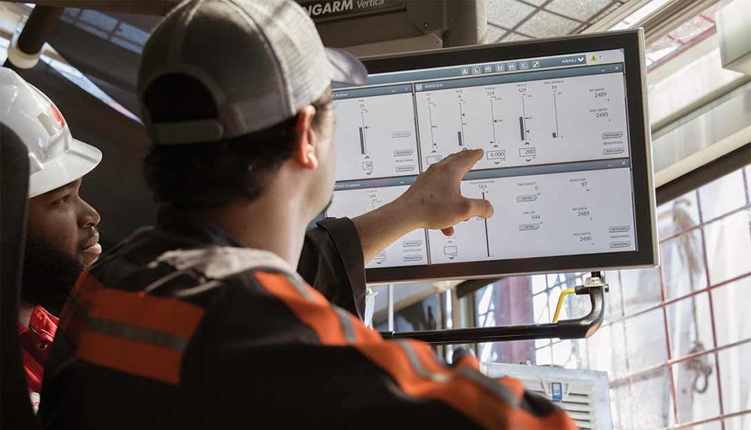 Man on in a drilling cabin points to a screen