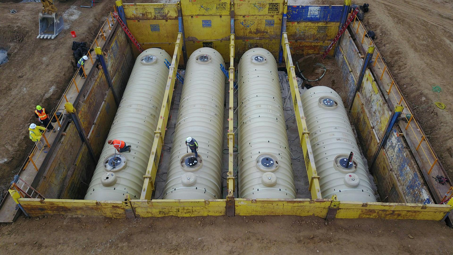 Underground installation of pipeline tanks, separated into 4 parts, with employees around and on the tanks