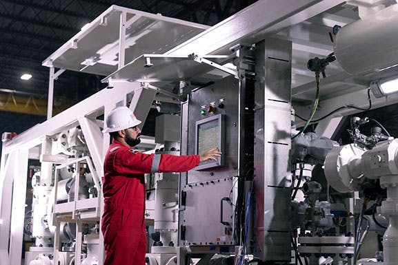 NOV employee working on a managed pressure drilling machine while wearing PPE