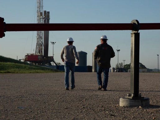 Two men wearing hardhats walking toward a tower