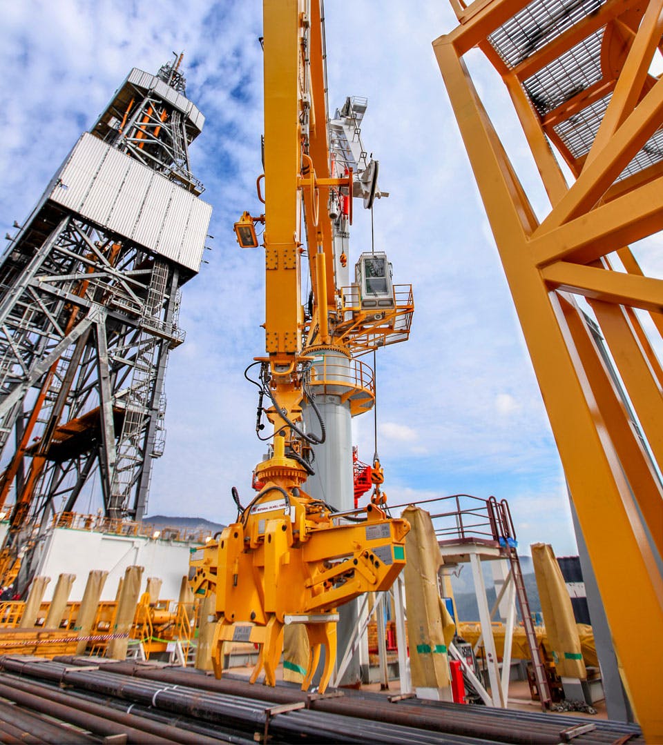 view of crane lifting pipe from below