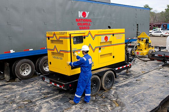 NOV employee working on a yellow generator while wearing PPE