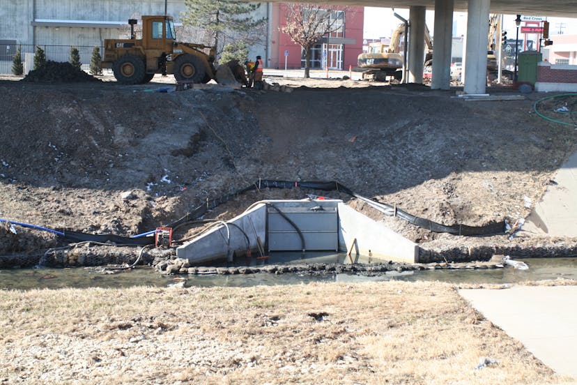 Solid dual rectangular flap gate installed at bottom of grassy hill. 